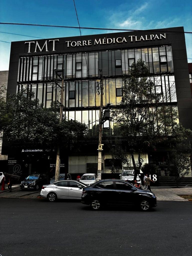 Modern black medical building TMT Torre Medica Tlalpan with large windows and cars parked in front under blue sky